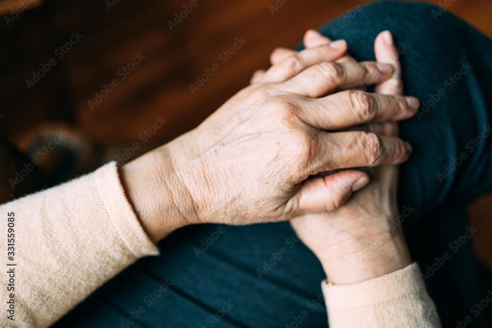 Fototapeta premium Two old woman's hands resting on her leg