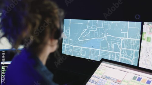 Closeup on female dispatcher focused on computer screens with rack focus