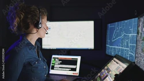 Handheld reveal of female emergency dispatcher with headset at workstation 