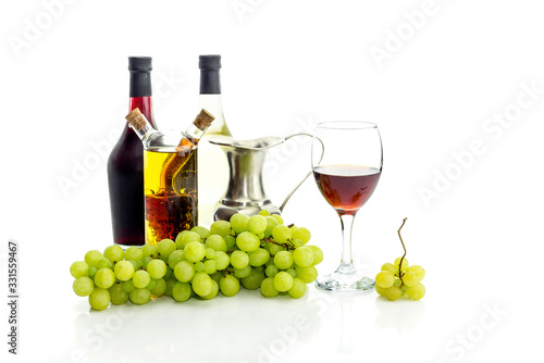 Bottles of wine, pitcher, wine glass and grapes on a white background close-up
