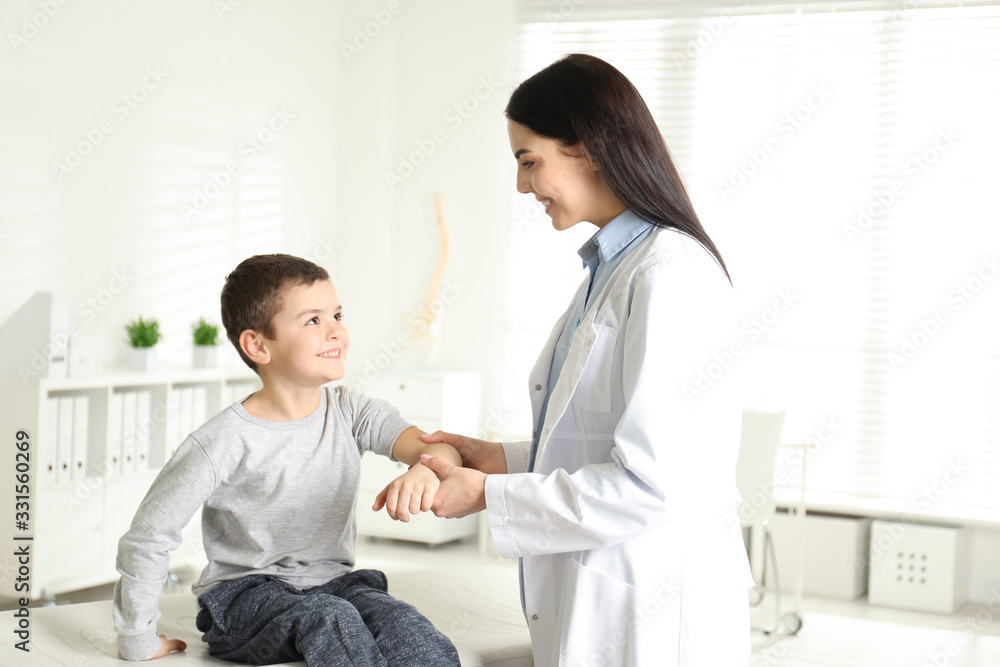 Fototapeta premium Professional orthopedist examining little patient's arm in clinic
