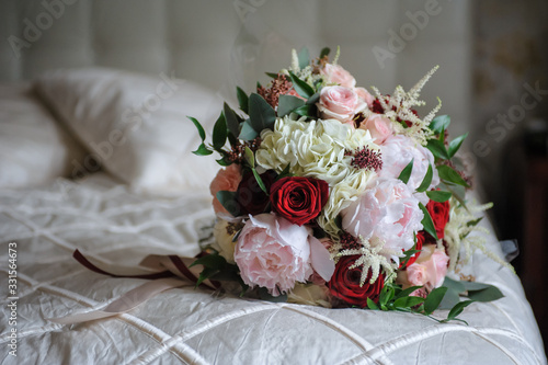 Colorful wedding bouquet on a bed. Bridal bouquet, white bedding. Luxury hotel room. Valentine's day or mother's day present