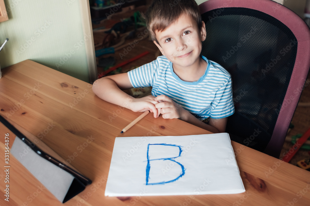 Happy child shows page with written letter B, home schooling Happy child shows page with written letter B, home schooling