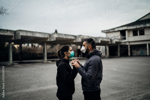 Two people in masks holding hands.Couple being divided by incurable infectious disease.Infection control,isolation.Loved one illness.Saying goodbye.Farewell.Letting go.Toxic relationship.