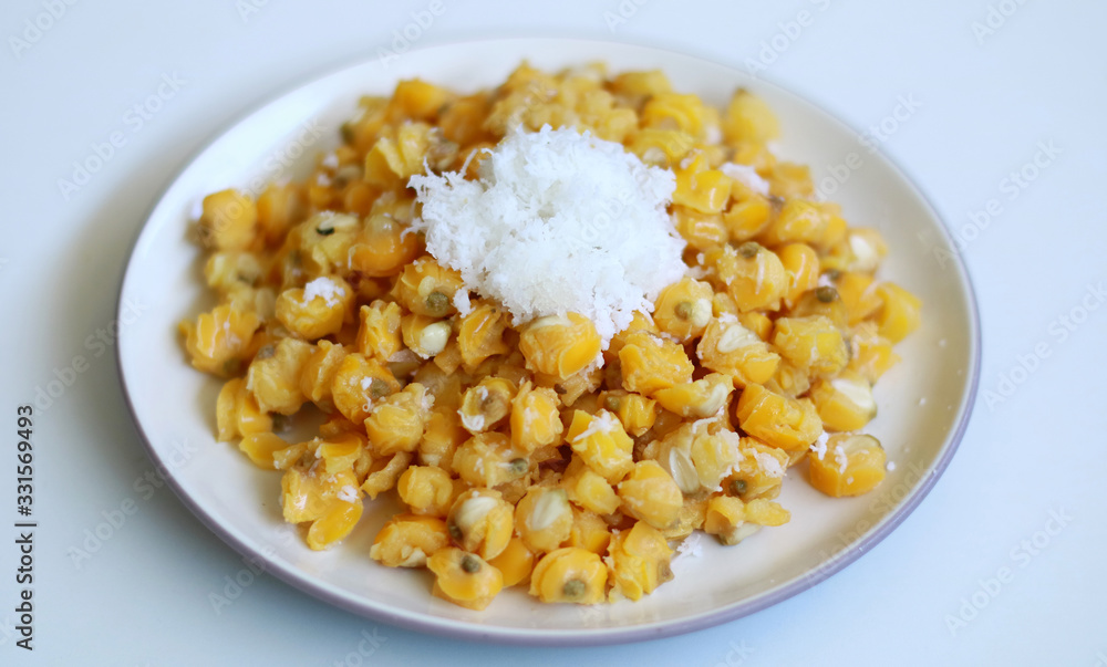 Grontol jagung on white background.  Grontol jagung is traditional snacks in Indonesia. Boiled shelled corn sprinkled with grated coconut.