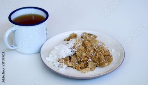 Tiwul and a cup of tea on white background. Tiwul is Indonesian traditional food. Made ​​from dried cassava (tapioca).                photo