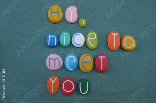 Hy, nice to meet you, creative text composed with multi colored stone letters over green sand