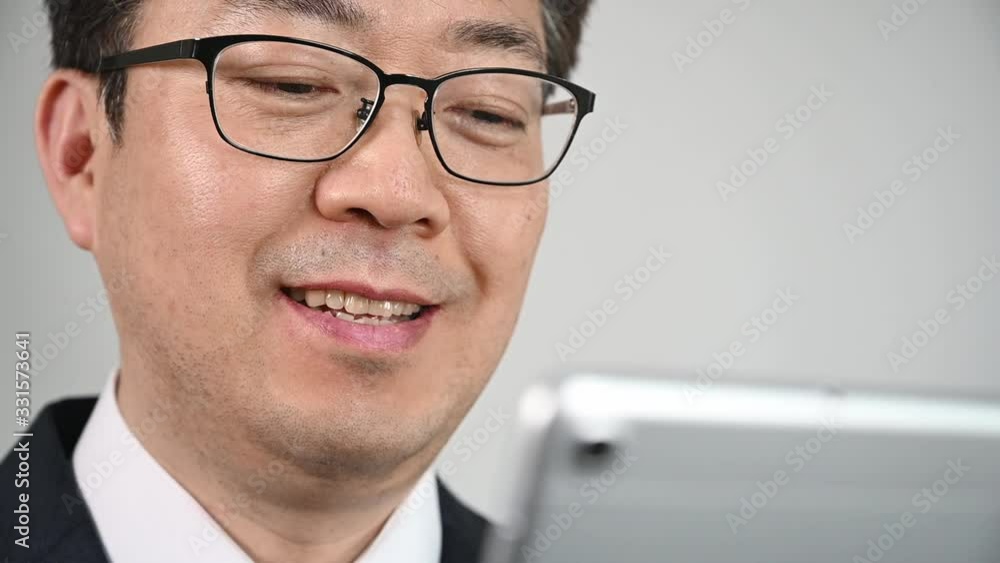 An Asian businessman who is using tablet to search for information or communicate. An Asian businessman who is using tablet to search for information or communicate.