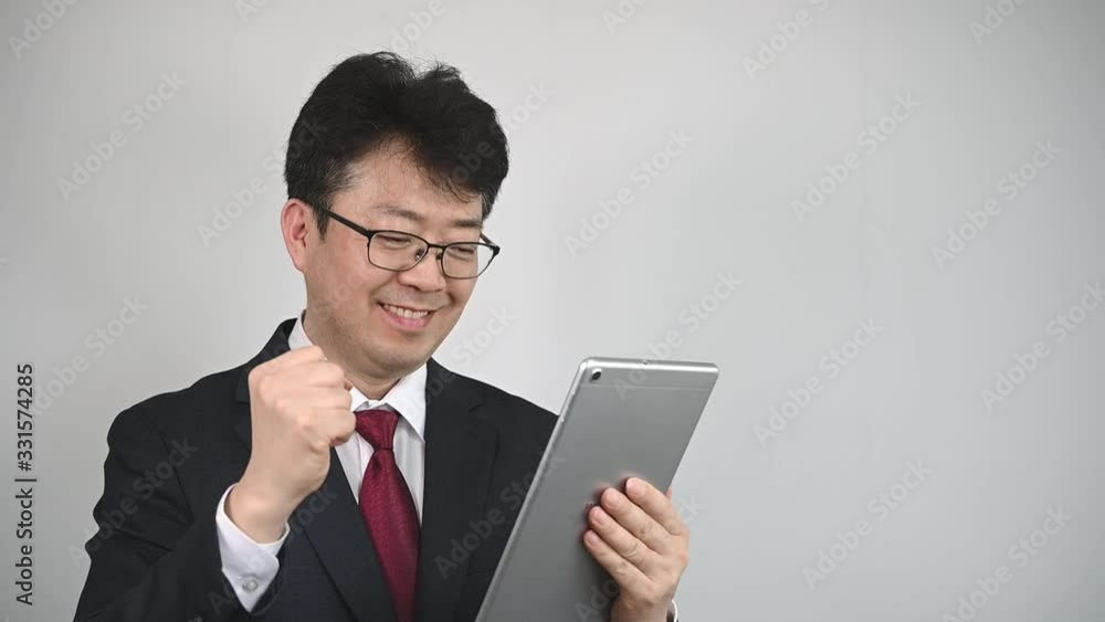 An Asian businessman who is using tablet to search for information or communicate. An Asian businessman who is using tablet to search for information or communicate.