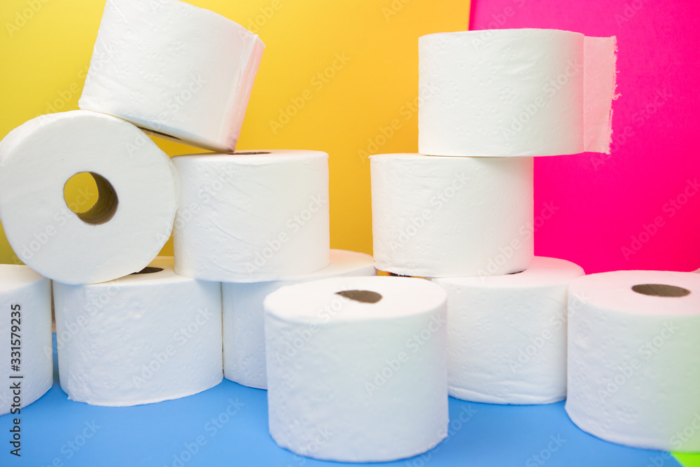 Stockpile of toilet paper rolls on colorful background. Many rolls at home in fear of corona virus outbreak closing shopping stores. Stockpile of toilet paper rolls on colorful background. Many rolls at home in fear of corona virus outbreak closing shopping stores.