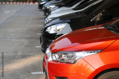 Closeup of front side of red car with  other cars parking in parking area. © Amphon