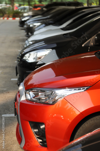 Closeup of front side of red car with  other cars parking in parking area. Vertical view. © Amphon