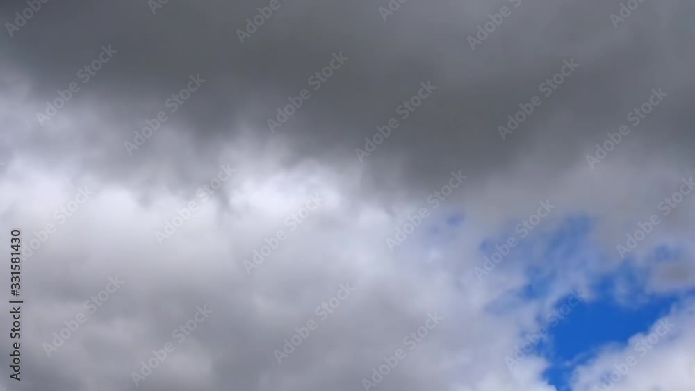 Time lapse of gray and white dark rain clouds moving through the sky with a patch of blue Time lapse of gray and white dark rain clouds moving through the sky with a patch of blue