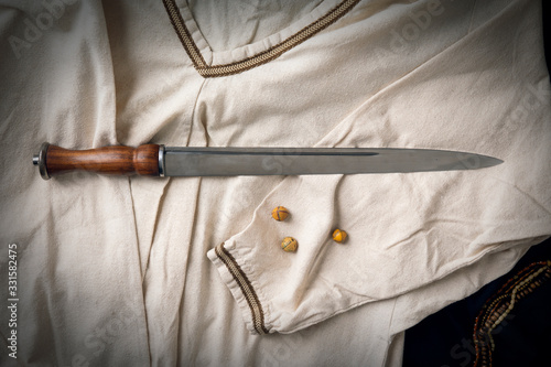 Viking dirk (dagger) arranged on a linen tunic with glass beads