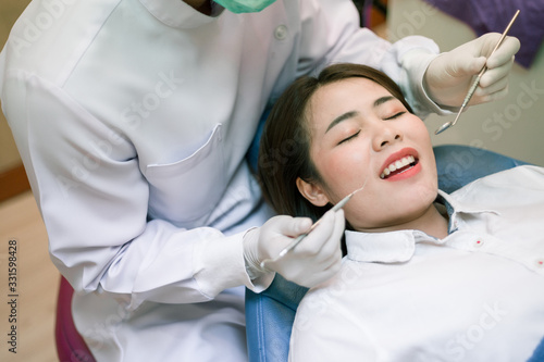 The woman came to see the dentist. She sits in the dental chair. The dentist bent over her. Happy patient and dentist concept.