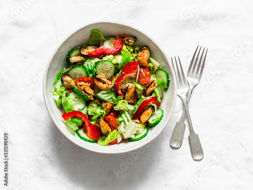 Salad with fresh vegetables and canned mussels on a light background, top view. Delicious healthy diet food