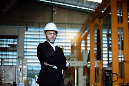 Portrait of young business boss with arms crossed smiling at camera while sit in factory. business factory SME concept.