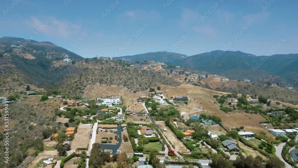 Drone camera shoots the canyon and the settlement at the foot of the mountain on a clear sunny day (Malibu, California, USA) Drone camera shoots the canyon and the settlement at the foot of the mountain on a clear sunny day (Malibu, California, USA)