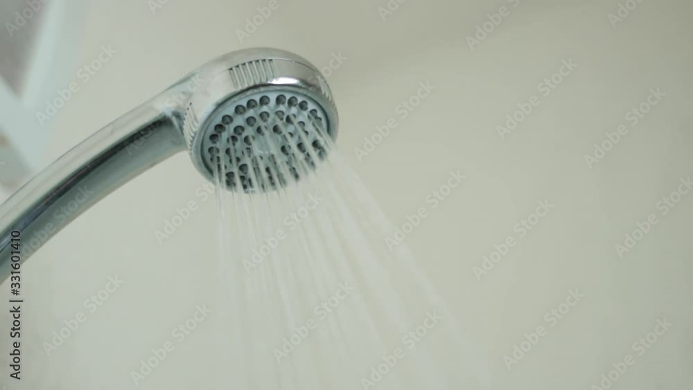 Closeup turning on and off shower head in bathroom, water flow front