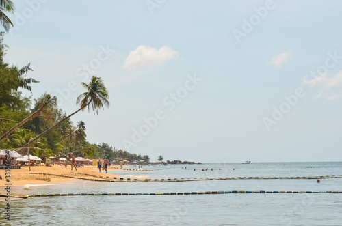 Fototapeta Naklejka Na Ścianę i Meble -  green palm trees and people on the public beach of Phu Quoc island Vietnam