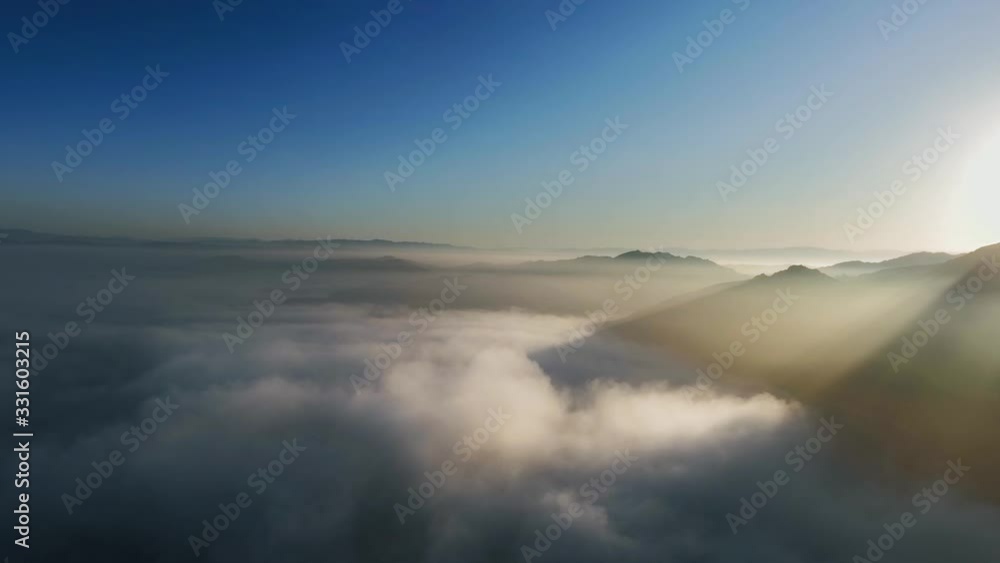 Aerial view of sunlight near billowing clouds and mountain peaks (Malibu Canyon, Monte Nido, California, USA) Aerial view of sunlight near billowing clouds and mountain peaks (Malibu Canyon, Monte Nido, California, USA)