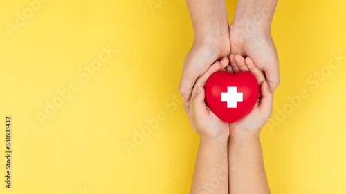 world red cross day, adult and child hands holding red heart, healthcare, love and family insurance concept photo