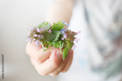 child hand holding a tiny bouquet of field flowers. gift for mother. selective focus