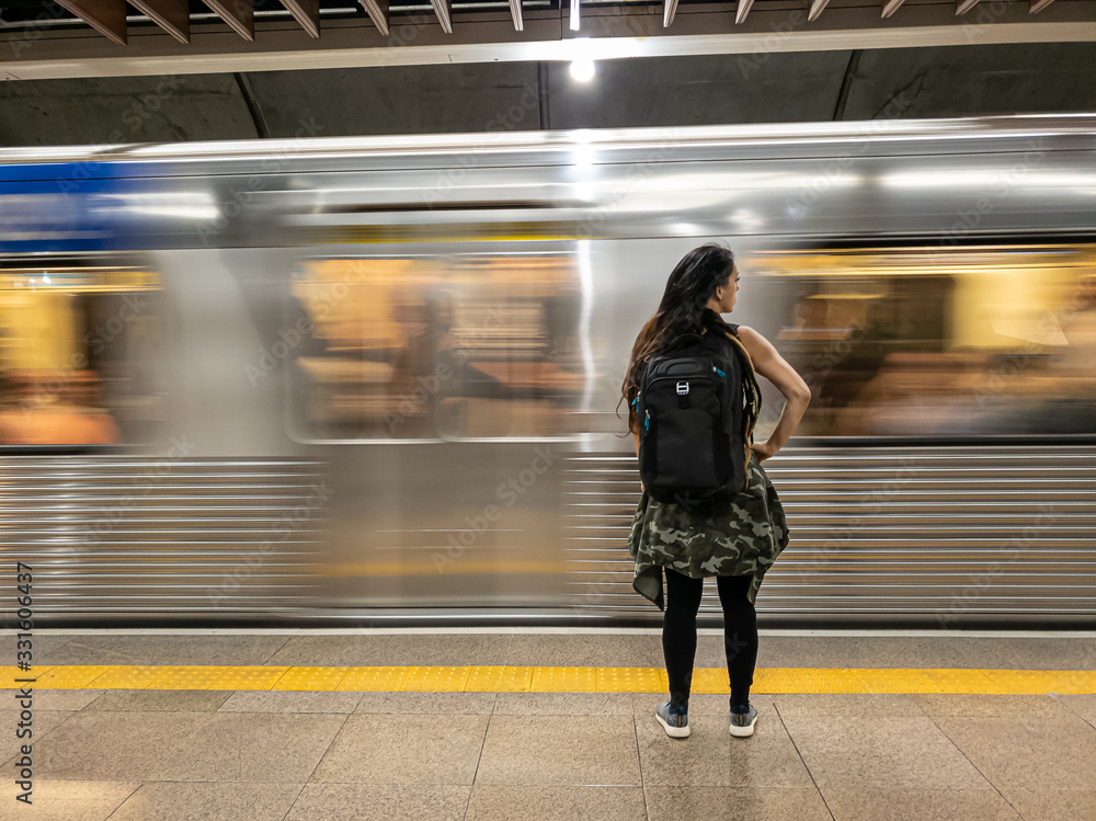 mulher vendo metro passar veloz na estação