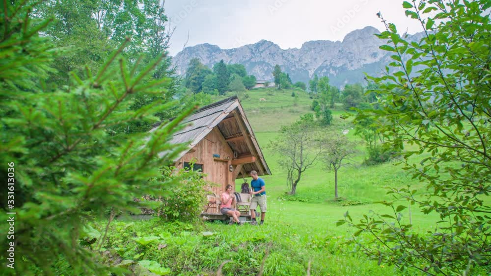Wanderer couple near a wooden house in the forest relaxing and having a drink. Wanderer couple near a wooden house in the forest relaxing and having a drink.