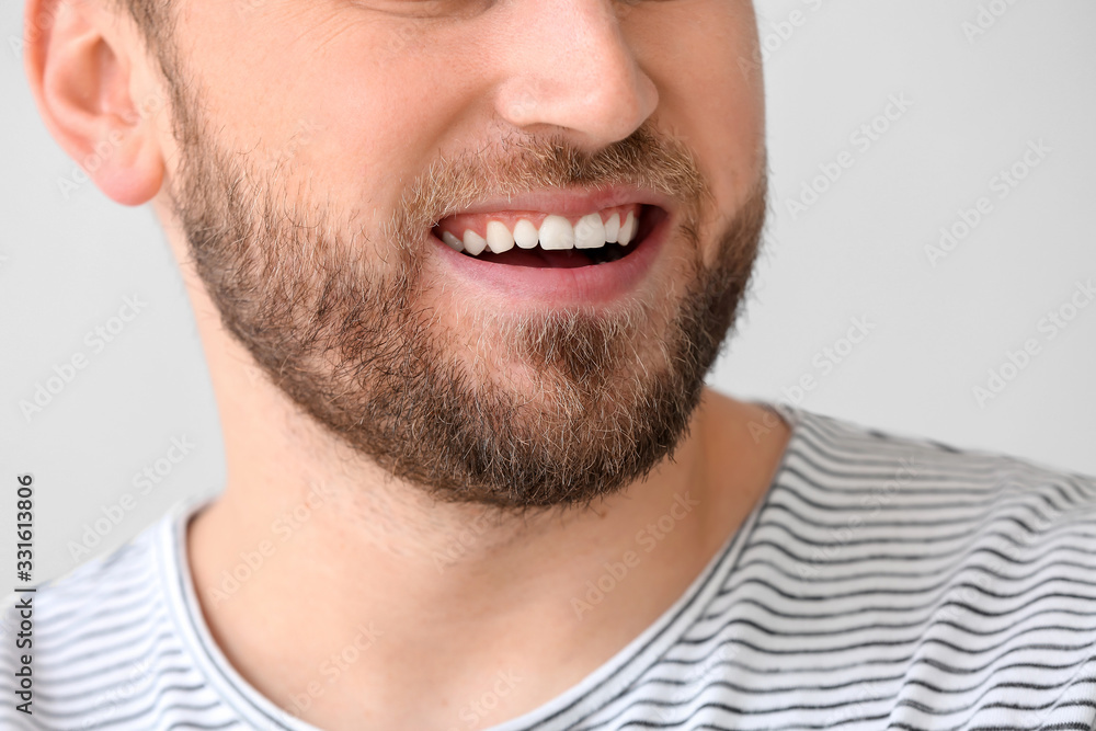 Obraz premium Smiling young man on light background, closeup
