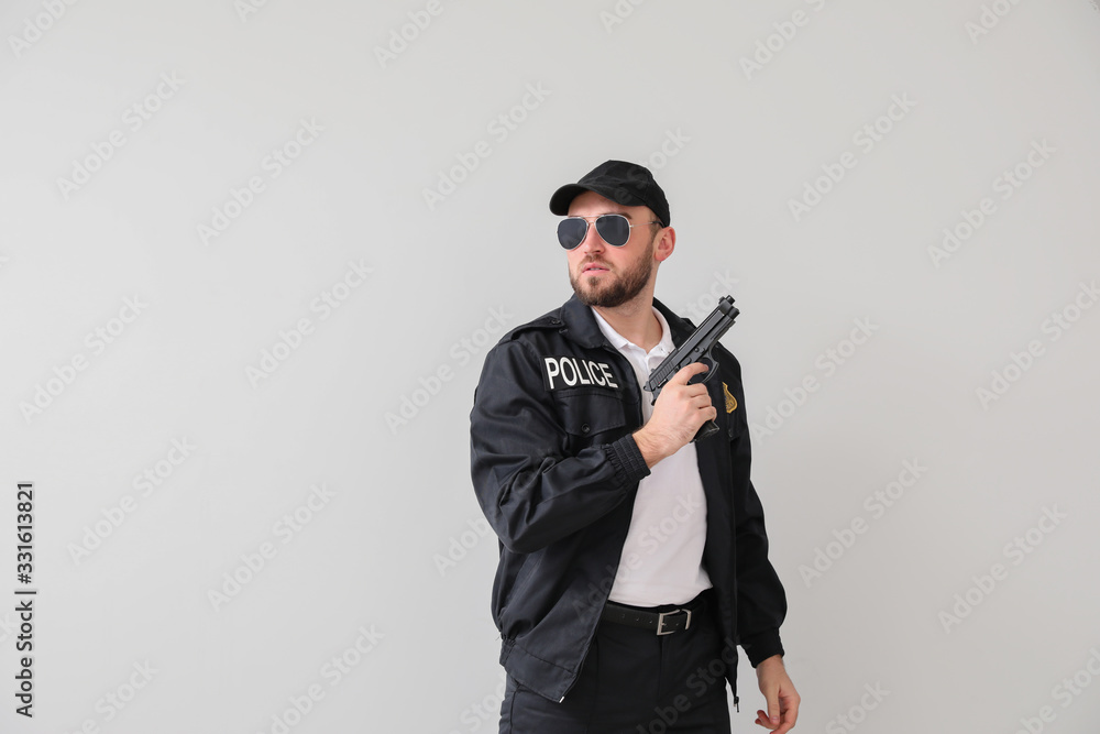 Male police officer with gun on light background Male police officer with gun on light background