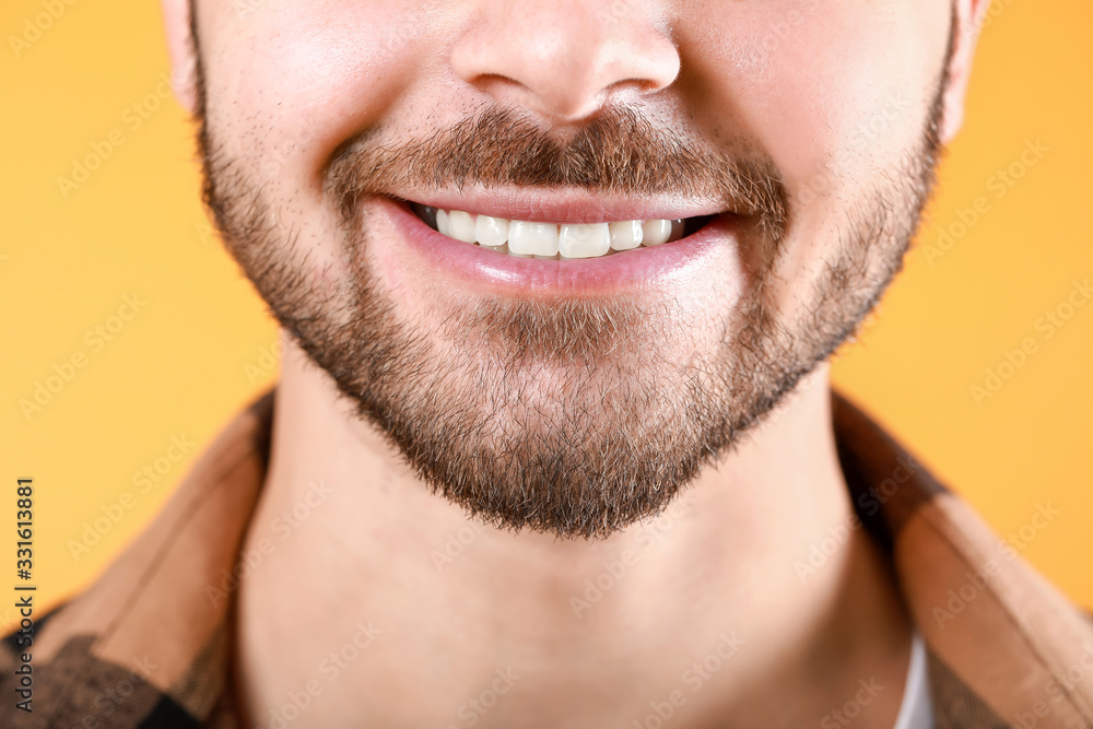 Fototapeta premium Handsome smiling young man on color background, closeup