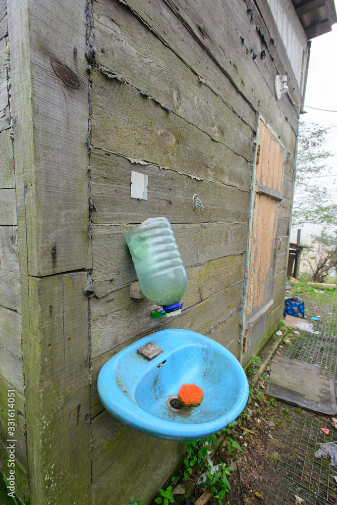 A plastic washstand with a sink hangs on a wooden wall in the summer. A plastic washstand with a sink hangs on a wooden wall in the summer.