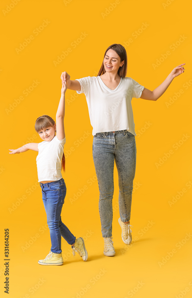 Happy mother and her little daughter dancing against color background Happy mother and her little daughter dancing against color background