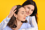 Portrait of adult daughter and her mother on color background