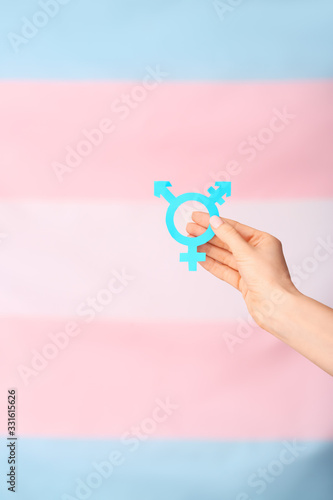 Female hand with symbol of transgender on color background photo