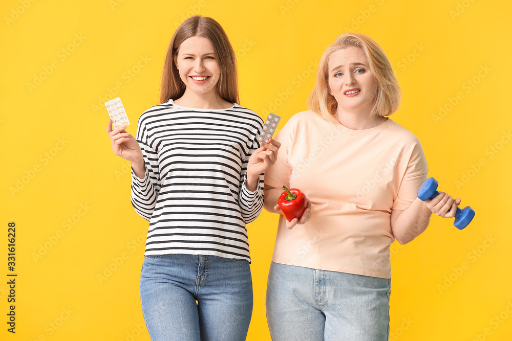 Women with weight loss pills, dumbbell and pepper on color background