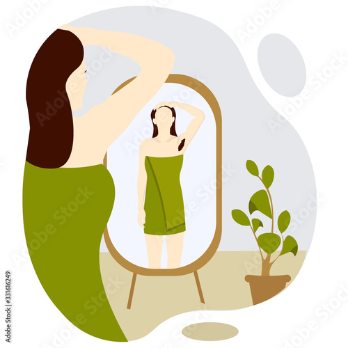 beautiful young woman after shower looking at herself in floor mirror. Girl wrapped a green towel. Visible hairy armpit. Concept Body positive and feminism. 