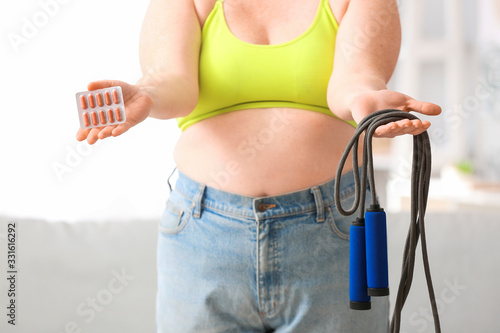 Woman with weight loss pills and jumping rope at home photo