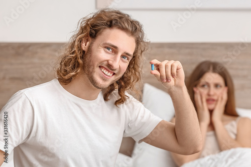 Obraz na płótnie Young man with oral erectile dysfunction medication and his wife in bedroom