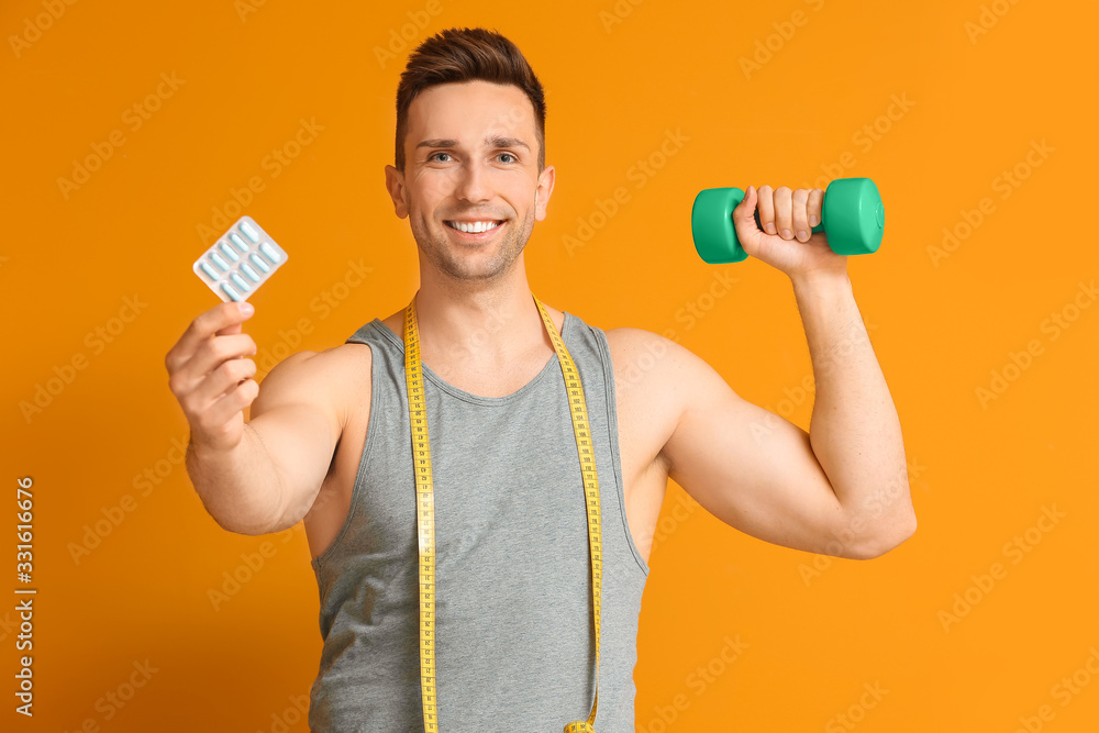 Young man with weight loss pills, measuring tape and dumbbell on color background Young man with weight loss pills, measuring tape and dumbbell on color background
