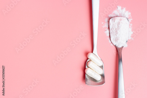Capsules and collagen powder in spoons on pink background, copy space. photo