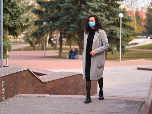 Young beautiful woman walks down the street in a medical mask so as not to get infected Coronaviridae 2019-ncov © Oleg Pogozhikh