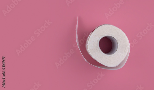 A roll of white toilet paper on a pink background copy space. Shortage of toilet paper flat lay. photo