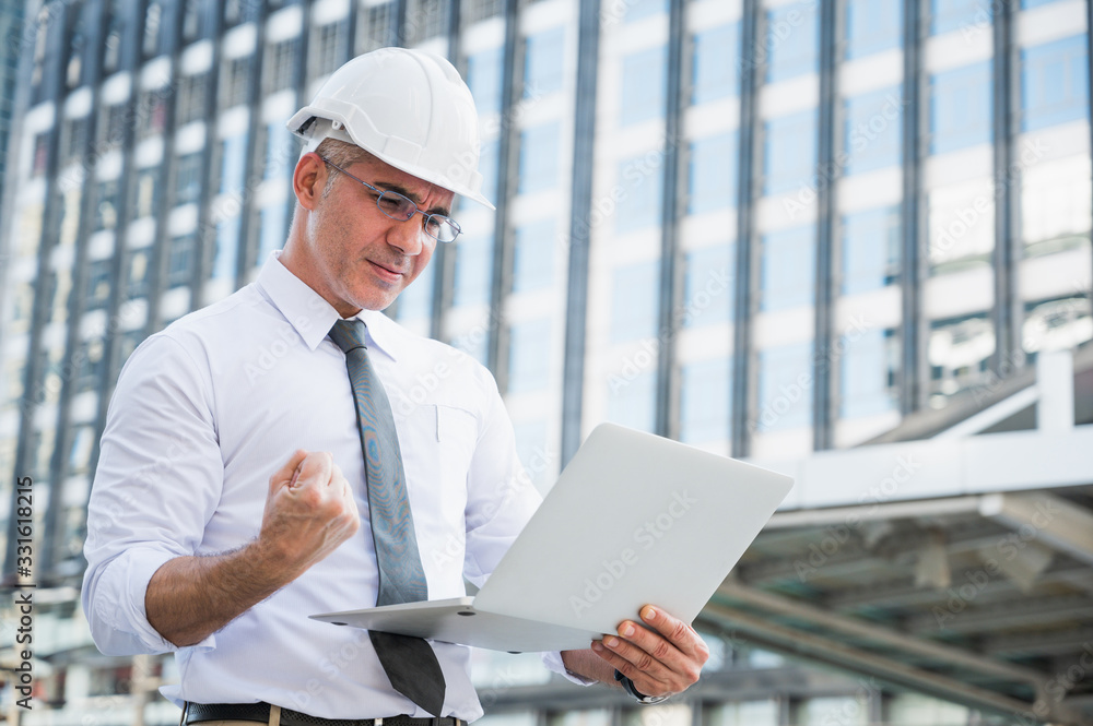 Civil engineering using laptop while working on building construction site and feeling happy with his project. Civil engineering using laptop while working on building construction site and feeling happy with his project.