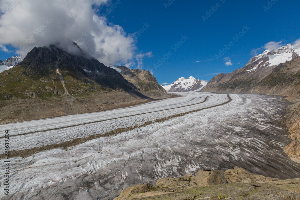 Aletsch glacier in Swiss mountains with blue sky and clouds