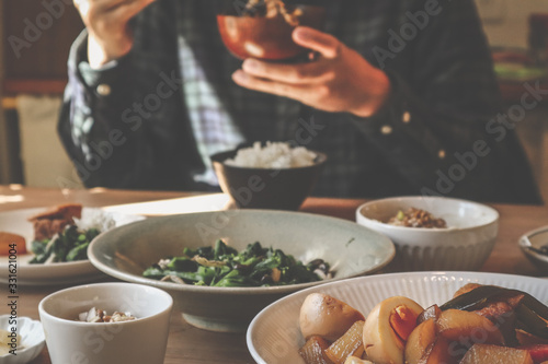 男性が味噌汁茶碗を持つ食事風景