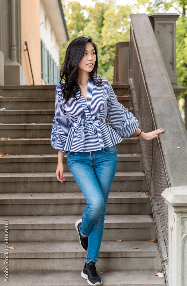 Fototapeta premium Young Asian Girl walking down stairs in Europe city. Europe city woman traveller lifestyle. Travel Europe summer holiday girl enjoying her holiday. Vacation and Holidays in Zurich and Europe concept.