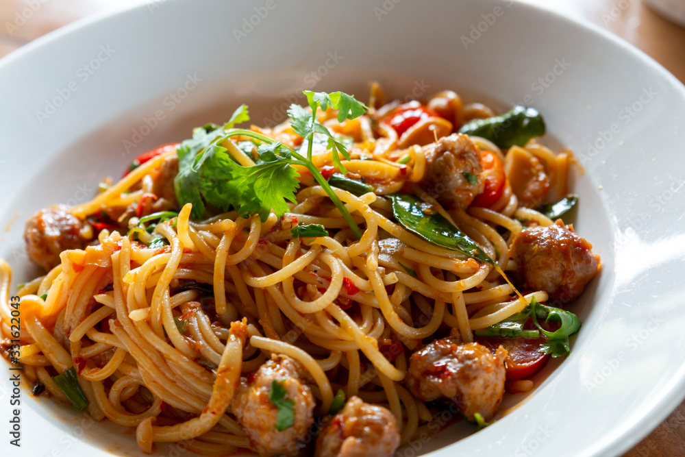 Selective focus, Spaghetti pasta with meatballs and tomato sauce. spaghetti and meatballs with oregano garnish on white plate. Spicy Spaghetti pasta with meatballs and spicy sauce.