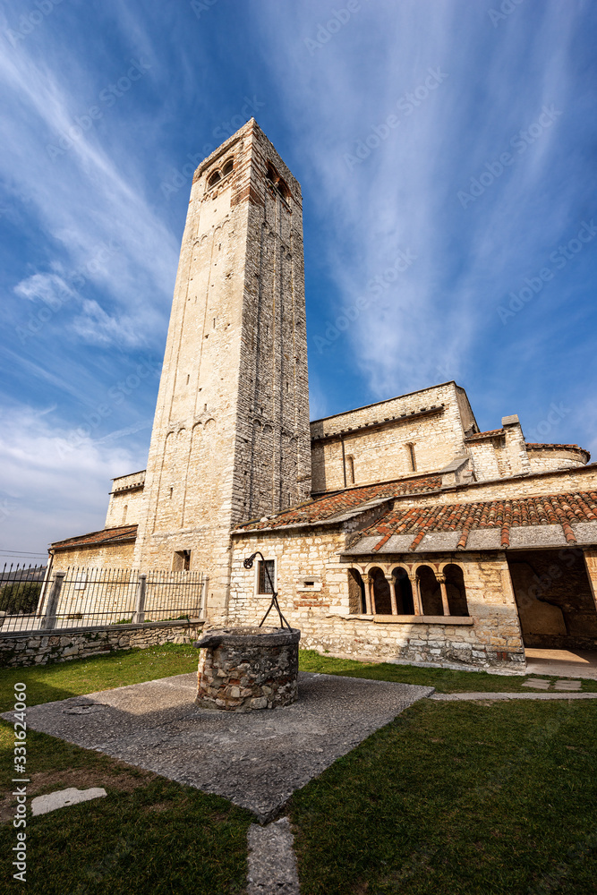 Ancient Romanic parish Church of San Giorgio di Valpolicella or Ingannapoltron (VII - XI century), with the bell tower, the cloister and the well. Veneto, Verona province, Italy, Europe